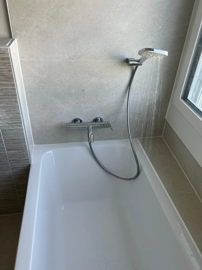 Badewanne mit Regendusche und Wandmischer nach Badsanierung